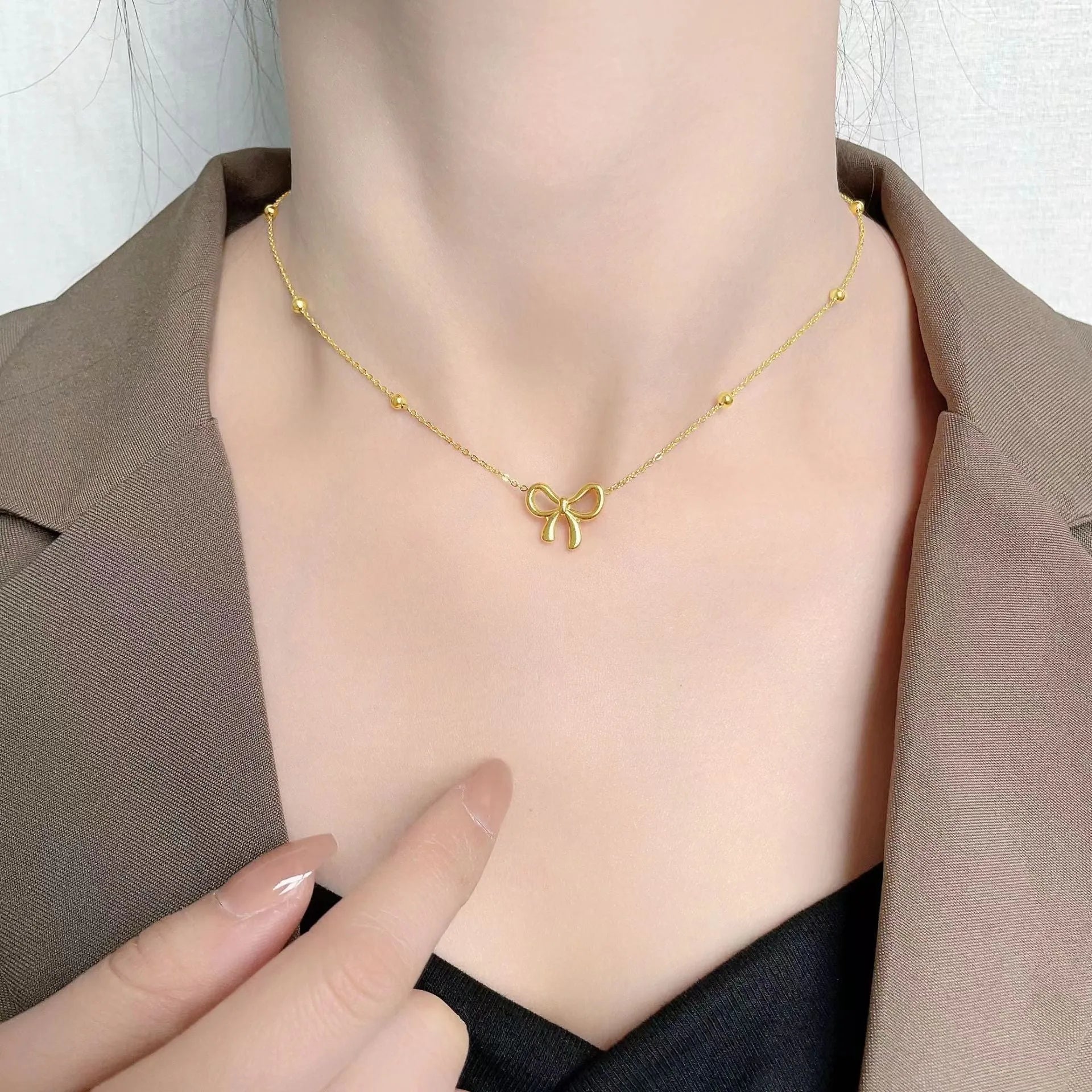 Gold-colour titanium steel necklace with a bow pendant on an adjustable chain