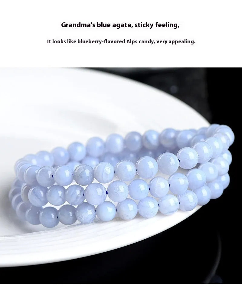 Close-up of a blue agate bracelet with multi-circle patterns, striped beads, and a Ruyi element on a neutral background.