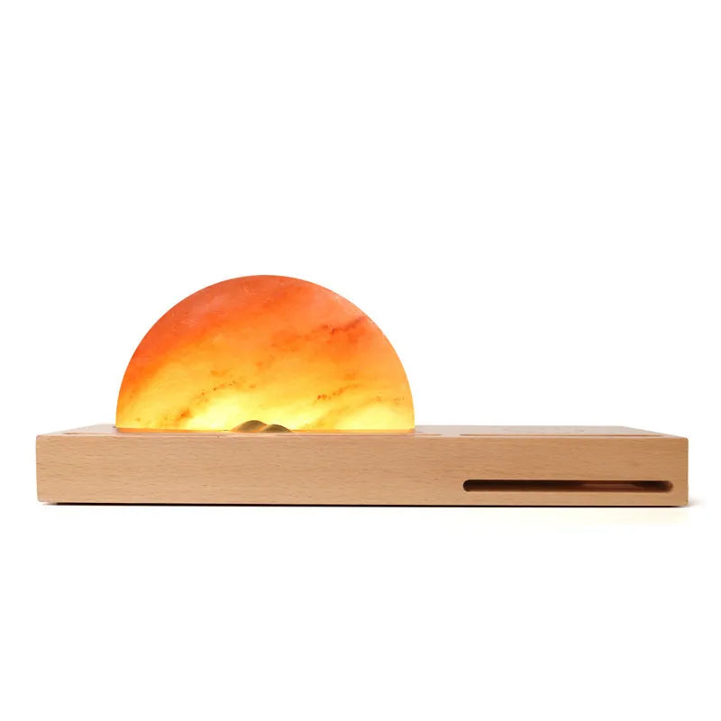 Natural crystal salt lamp with wireless charging pad on a light beech wood table base.