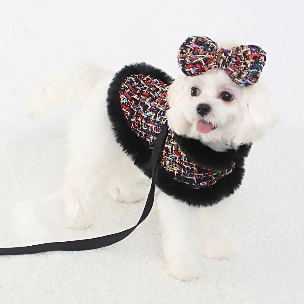 A dog wearing a classic cloth cloak chest harness with an attached hand holding rope.