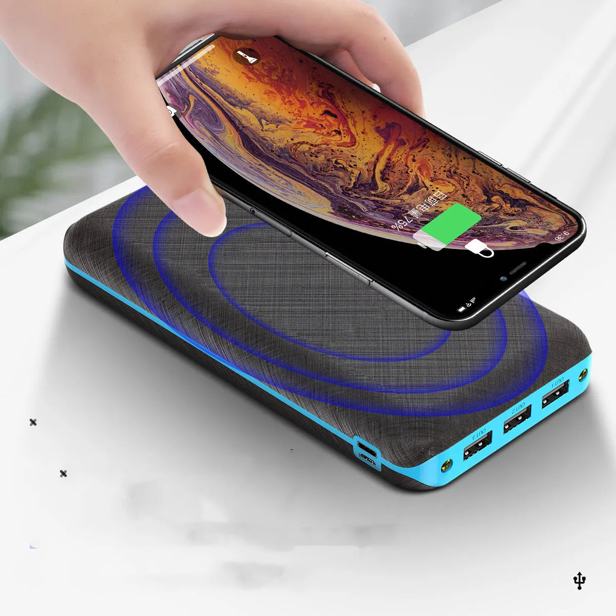 Black portable power bank with Qi wireless charging pad and three USB ports on the side