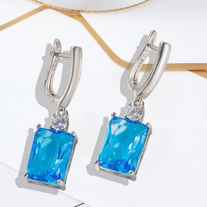 A pair of square-shaped gold and silver electroplated copper earrings showing front view.