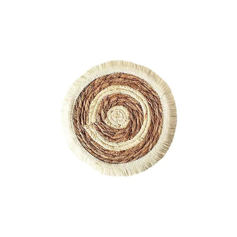 A round natural papyrus straw placemat with decorative tassels, shown in a solid colour.