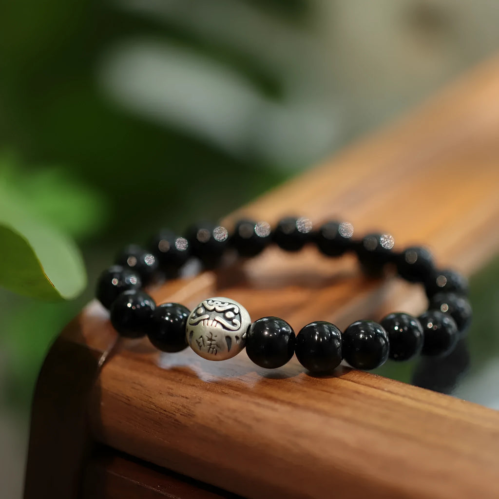 Close-up of a black agate and sterling silver bracelet with 10mm beads and a manual polish finish.