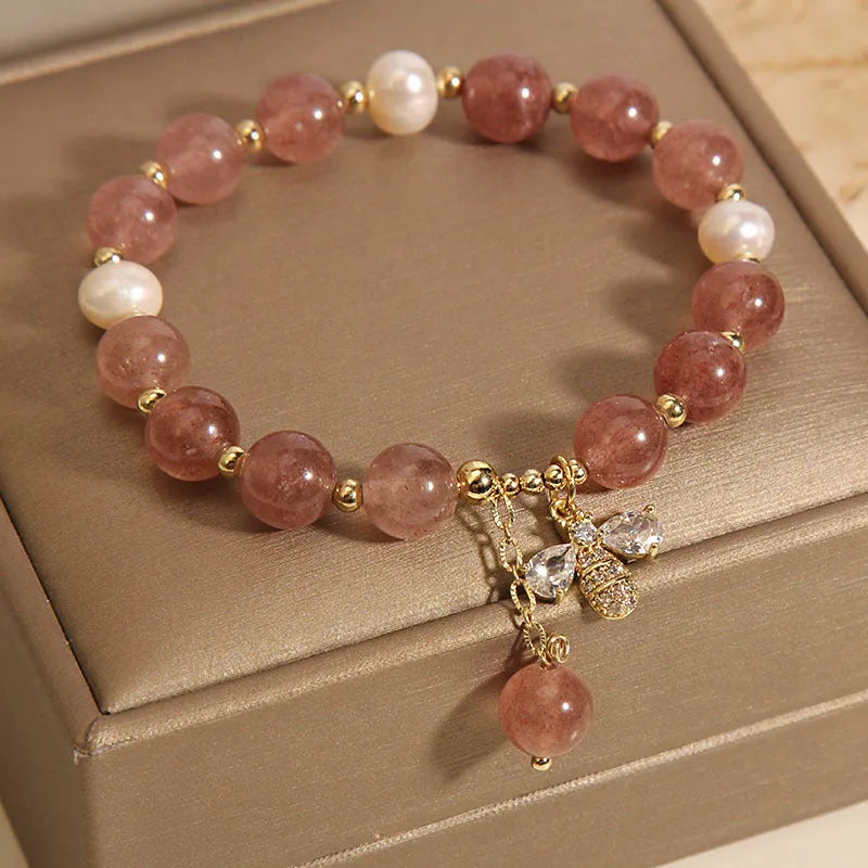 Close-up of a women's bracelet with pink strawberry quartz stones, white freshwater pearls, and sparkling zircon accents on an alloy clasp.
