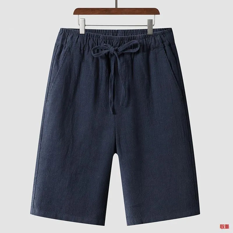 A pair of beige linen shorts for men with a loose, cropped fit and a mid-rise elasticated waistband.