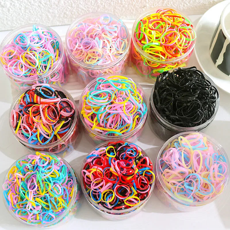 Assortment of colourful small TPU baby hair ties in a reusable plastic container.