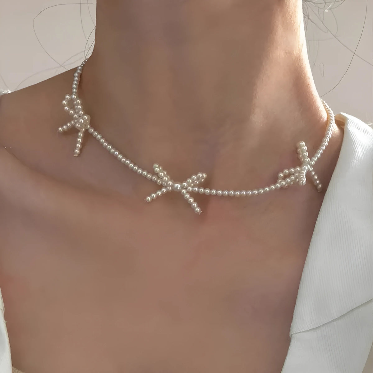 White imitation pearl necklace with a central bow pendant on a chain, adjustable from 31cm to 40cm.
