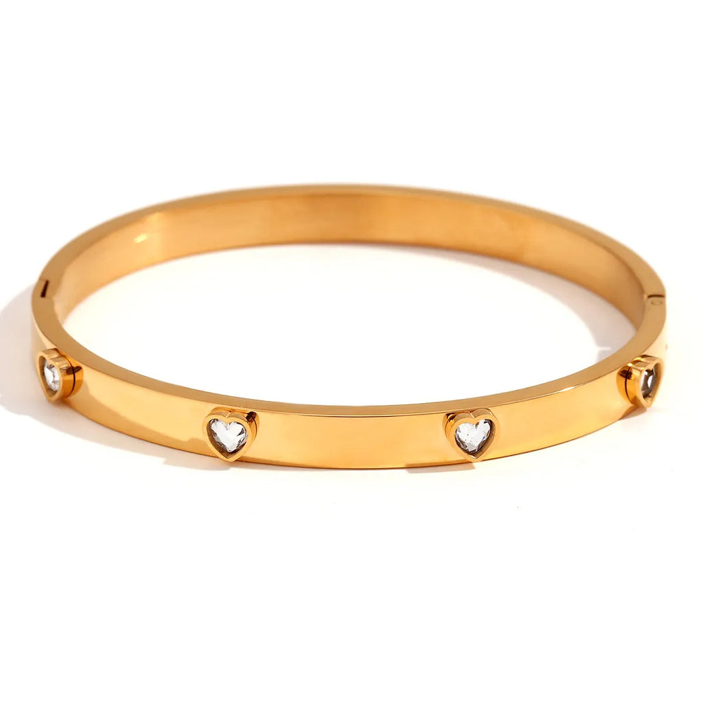 A stainless steel bracelet with a small micro-inlaid peach heart charm, shown in a golden electroplated finish.