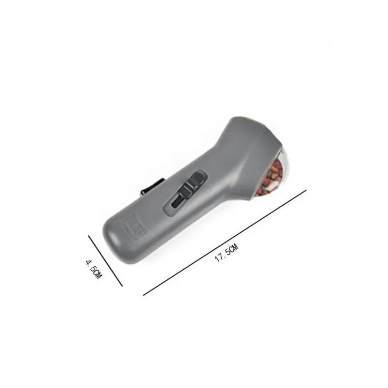 Grey pet snack catapult launcher toy on a table showing its size and spring trigger.