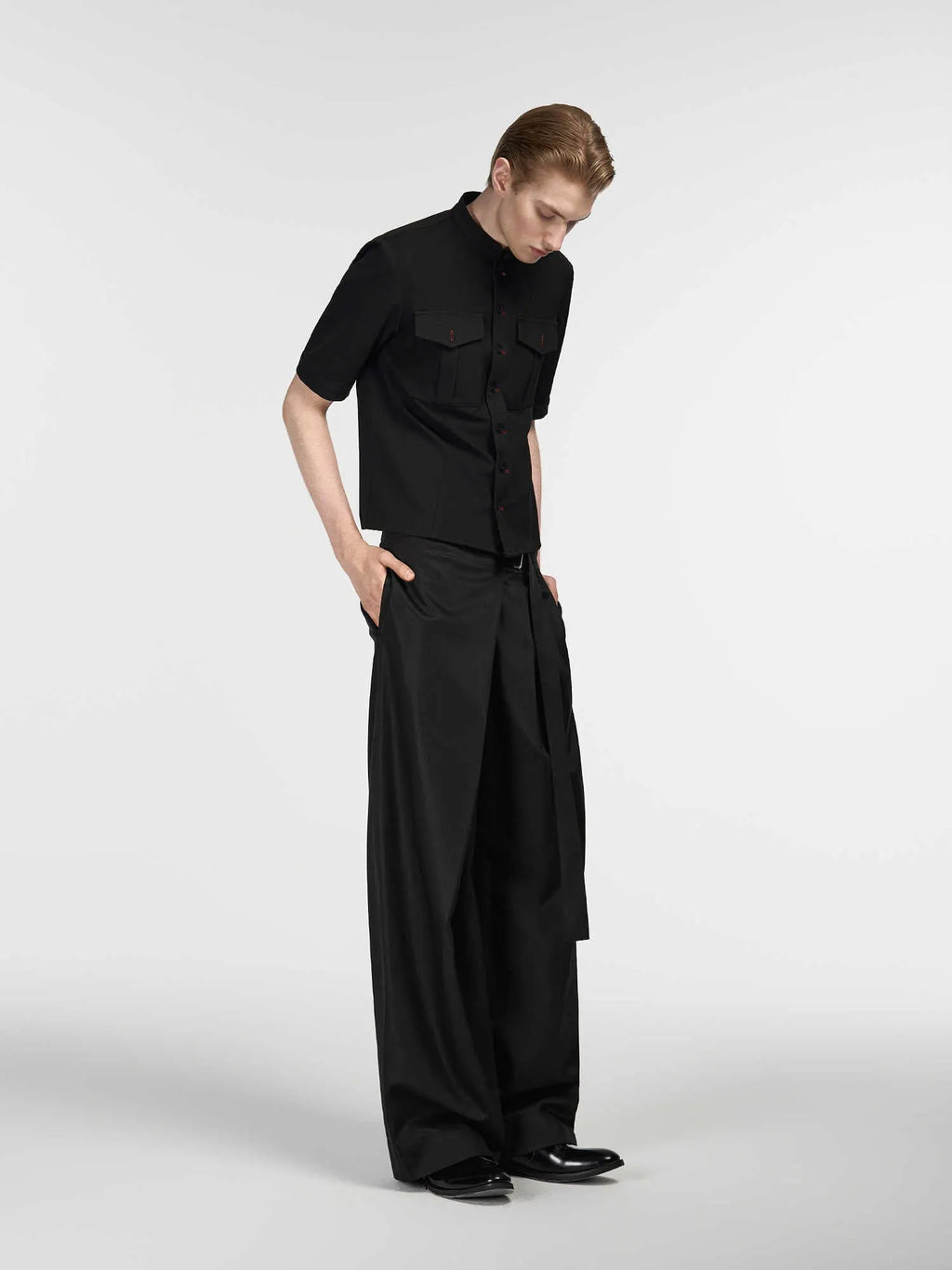 Black loose-fit straight-leg trousers with a single pleat and adjustable mid waist on a hanger.