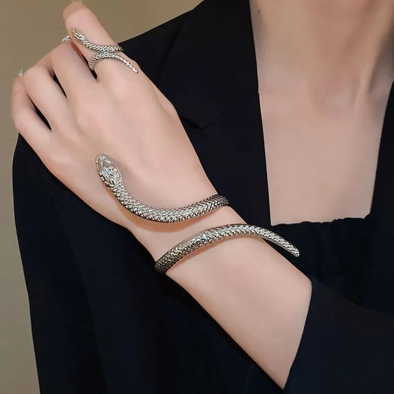 Gold twisted snake design metal bracelet and ring set on a white background.