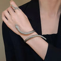 Gold twisted snake design metal bracelet and ring set on a white background.