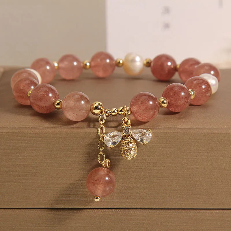 Close-up of a women's bracelet with pink strawberry quartz stones, white freshwater pearls, and sparkling zircon accents on an alloy clasp.