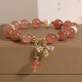 Close-up of a women's bracelet with pink strawberry quartz stones, white freshwater pearls, and sparkling zircon accents on an alloy clasp.