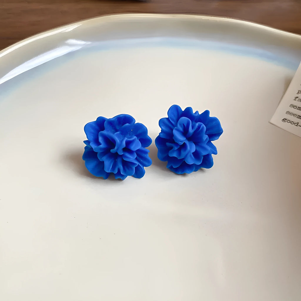 Geometric women's earrings with round blue cloth accents and silver metal details on a white background.