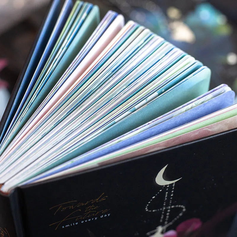 A5 notebook with luminous cover in blue, gold, light blue, or purple, open to show pages for colour illustration.