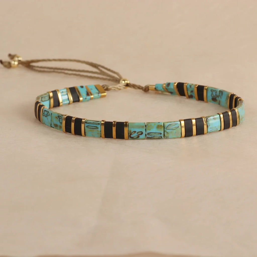 Geometric glass and coloured glaze beaded bracelet in milky white on a wrist.
