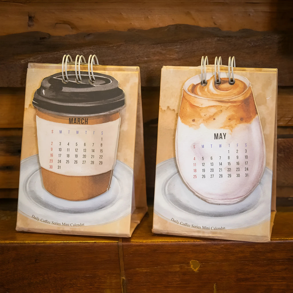 Coffee themed mini desk calendar for 2025 showing four different model designs on a desk.