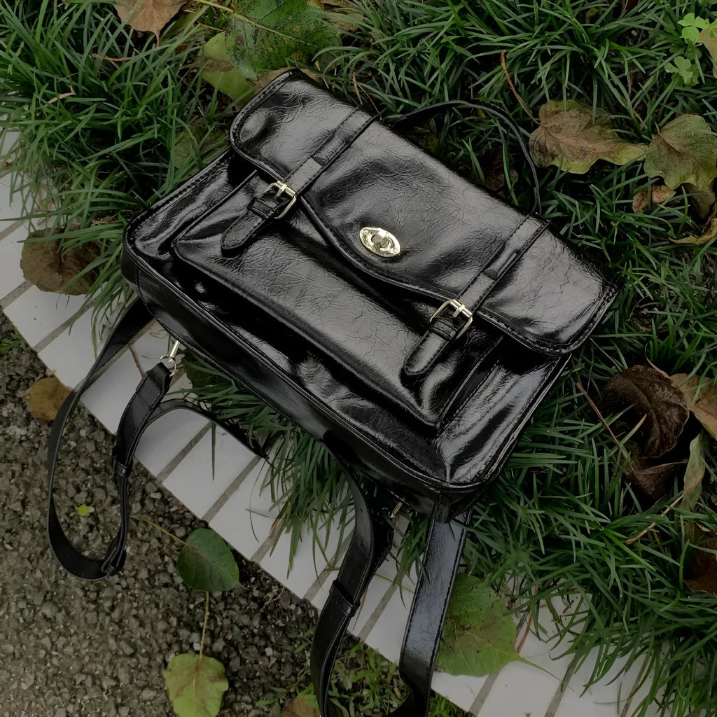 Black college messenger bag with oil wax leather finish showing crossbody strap and satchel design