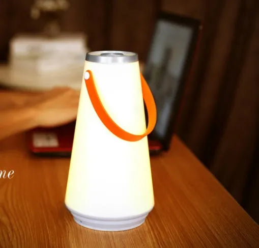 White rechargeable LED bedside lantern with warm light, shown next to a USB charging cable.