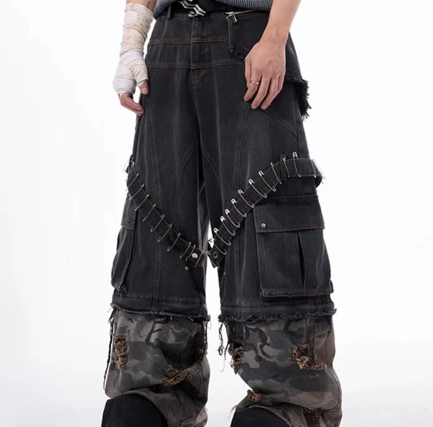 Men's grey camouflage pattern jeans with spliced panels and decorative pin details.