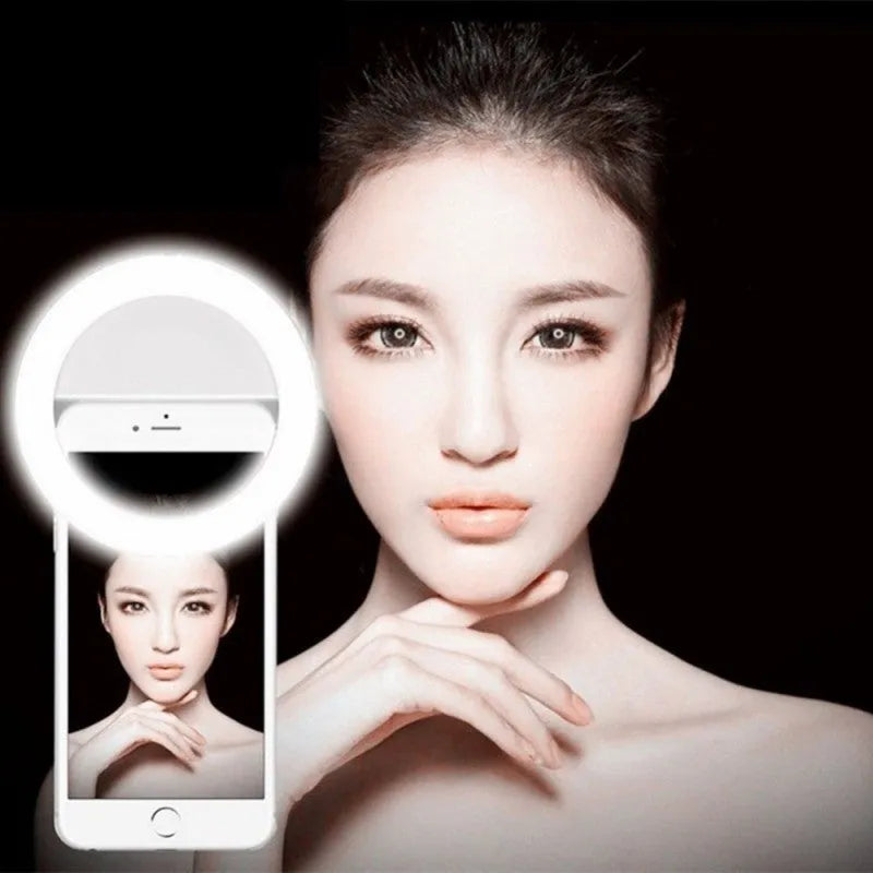 Green clip-on selfie ring light with LED bulbs attached to a mobile phone for dark environment photography.
