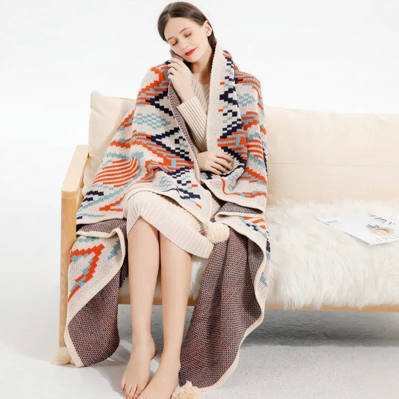 Bohemian style acrylic blanket with tassel fringe on a sofa, shown in a geometric print colour.