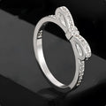 Silver colour bow-shaped ring with rhinestone and zircon crystal decoration on a finger.