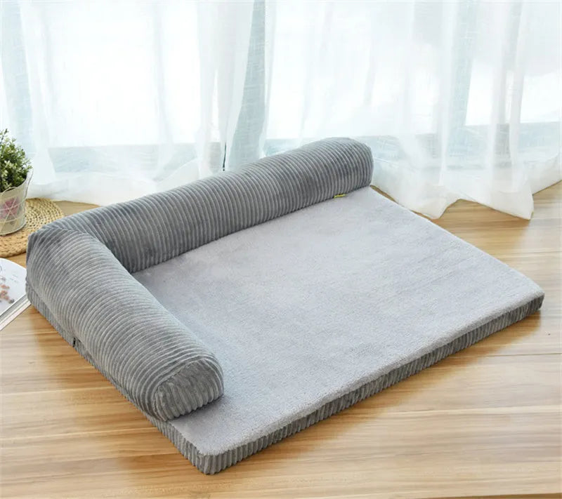 Corduroy dog sofa bed with bolster sides in a grey colour, shown on a wooden floor.