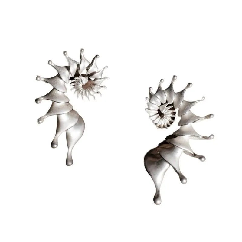 Close-up of a pair of matte-finish, three-dimensional conch shell stud earrings.