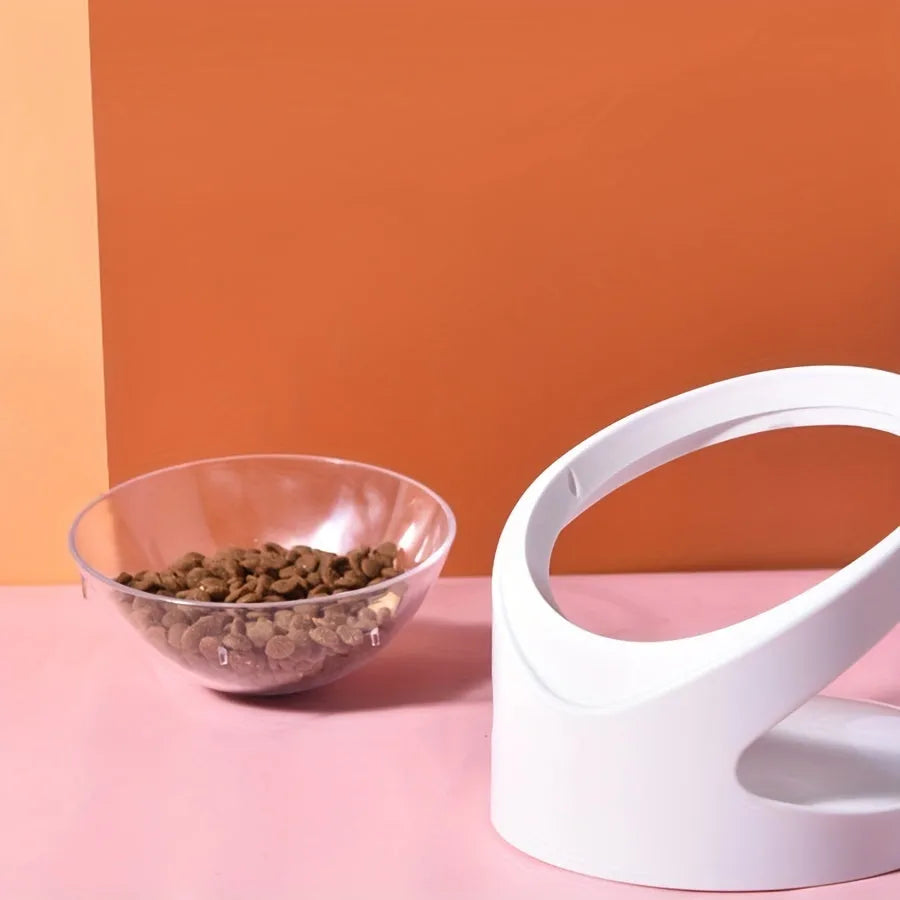 White clear plastic tilted cat food bowl on a flat surface.
