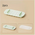 Ice cube tray with grid design and attached ice shovel stored in dedicated compartment