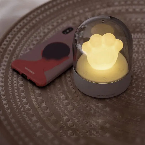 Grey and pink cat paw shaped USB rechargeable night light with adjustable brightness on a desk.