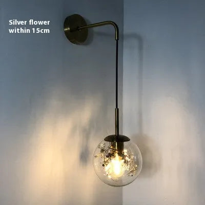 Small modern glass wall lamp in golden flower or silver flower finish for bedside lighting.