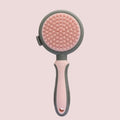 Green and pink two-sided pet grooming brush with a slicker head and a silicone massager head on a textured handle.