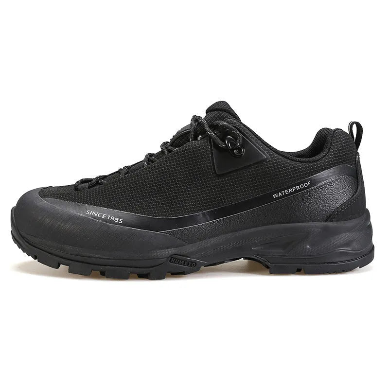 Men's low-top hiking boots in black with leather mesh upper and rubber outsole on a rocky path.