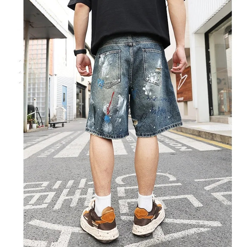 Blue ripped men's denim shorts with graffiti print and straight-leg cut.
