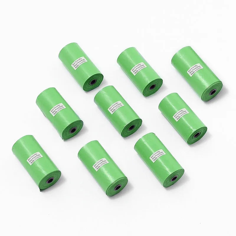 Roll of green EPI degradable dog poop bags next to a white dispenser on a table.