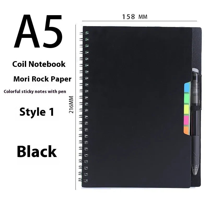 Erasable coil notebook with stone paper, showing a black cover option and a pen on a wooden desk.