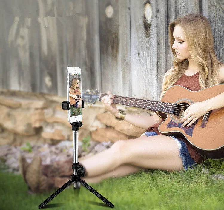 Black Bluetooth selfie stick with extended tripod legs and a phone clip rotated for horizontal filming.