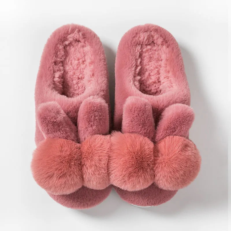 Women's fluffy bunny slippers with rabbit fur upper in cream colour on a wooden floor.
