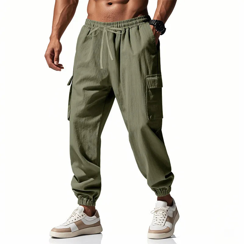 Man wearing loose-fit linen trousers with ankle-tied cuffs and a multi-pocket tether detail.