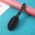 Black and pink plastic hair extension comb with ring teeth and an airbag, measuring 22cm by 6cm