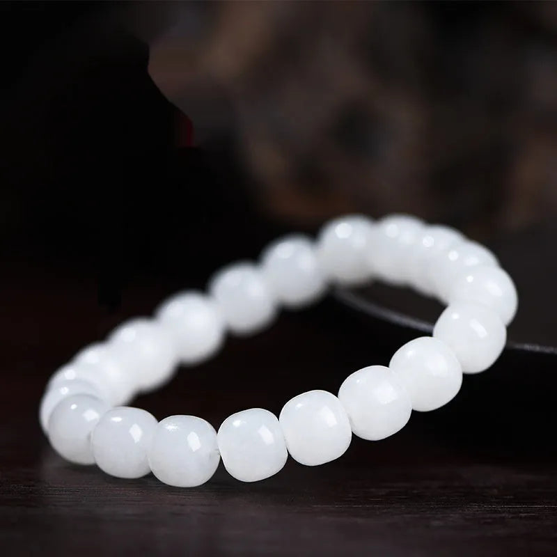White Hetian jade barrel bead bracelet on a wrist, showing the traditional bead design.