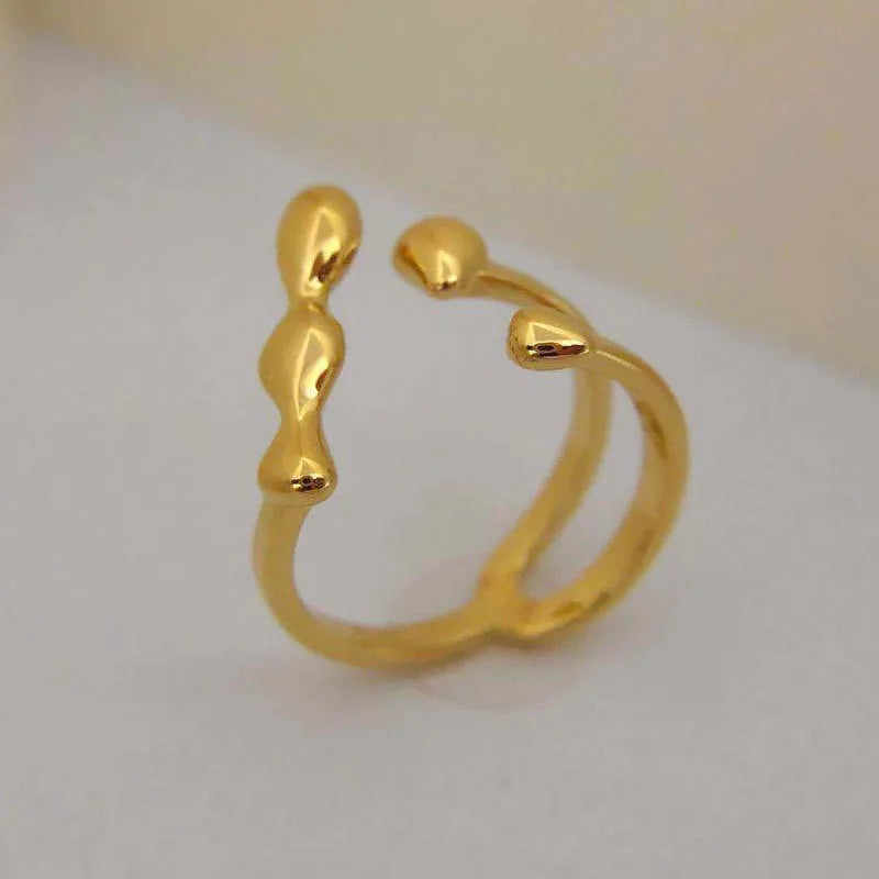 Brass opening ring with circle and sphere design in gold finish on finger