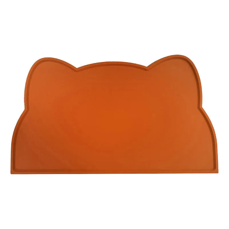 Blue silicone pet feeding mat with cat head shape under food and water bowls.