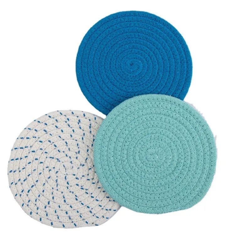 Set of three round grey cotton cord coaster placemats on a wooden table