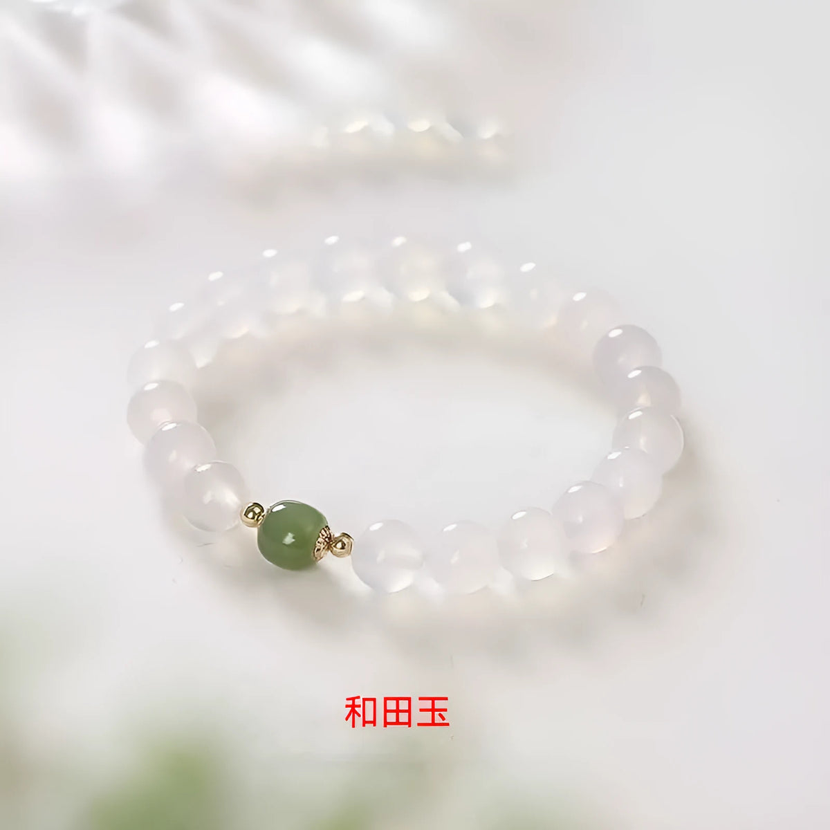 Handmade white agate bracelet with red cinnabar letter inlays on a wrist.