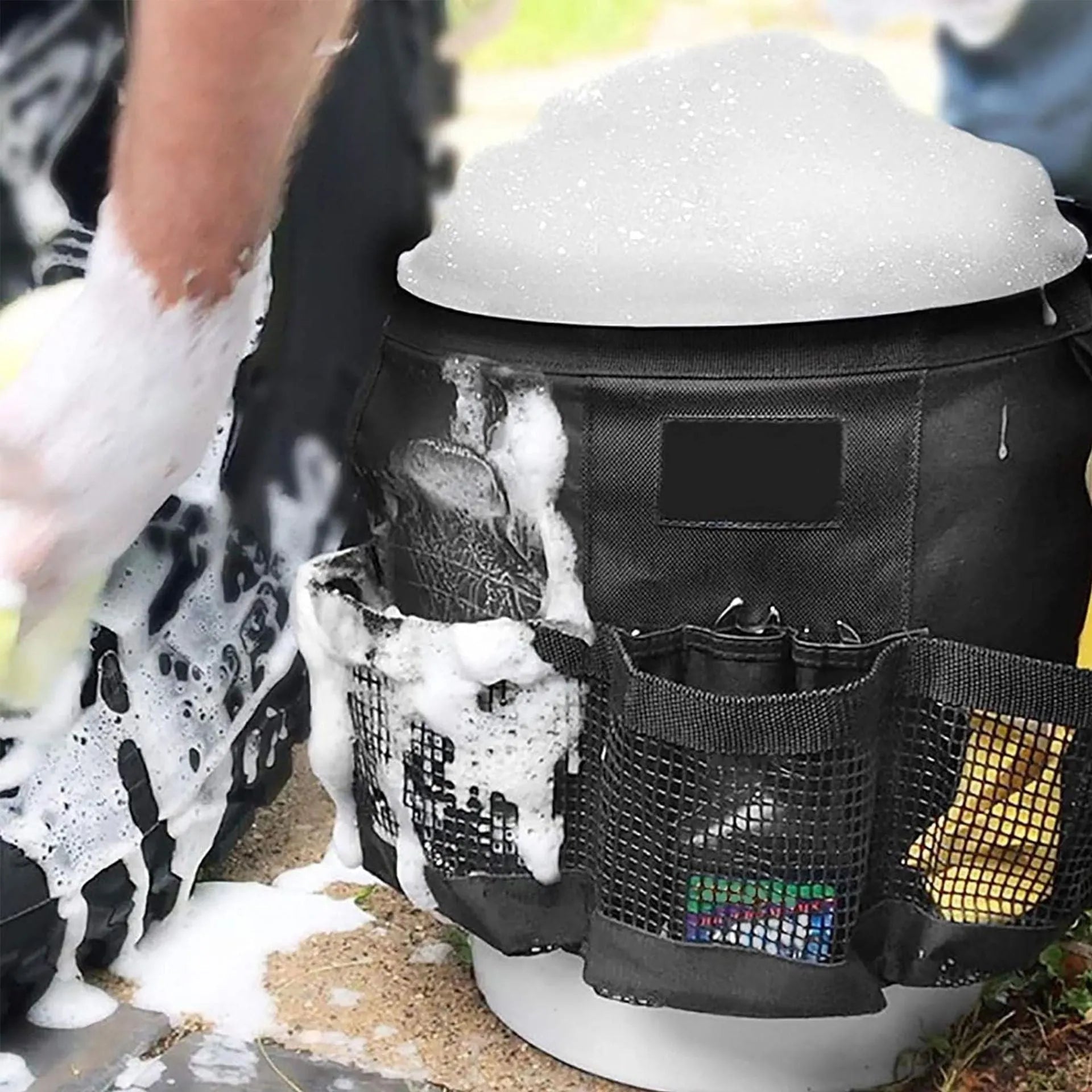Black cylindrical polyester storage bag hanging on a 5-gallon water barrel for organising tools and gear.